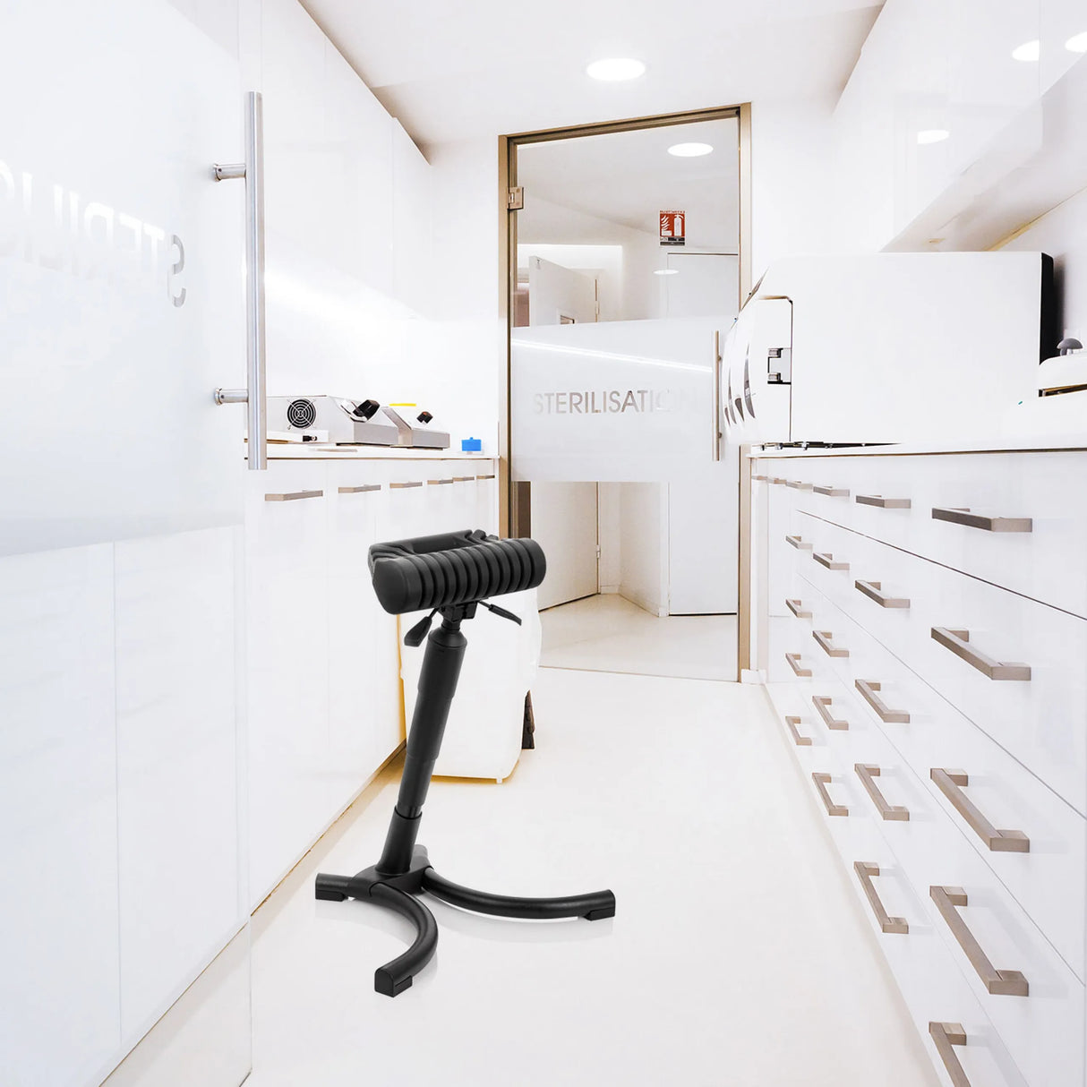 Schwarze Stehhilfe TOP WORK 33 mit gepolsterter Sitzfläche und Sternfuß in einer hellen Sterilisationsumgebung von hjh OFFICE