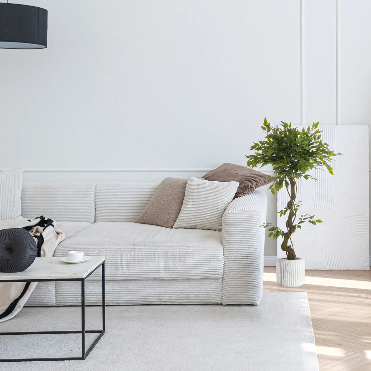 Grüne Kunstpflanze FICUS I in einem weißen Topf neben einem Sofa von hjh OFFICE