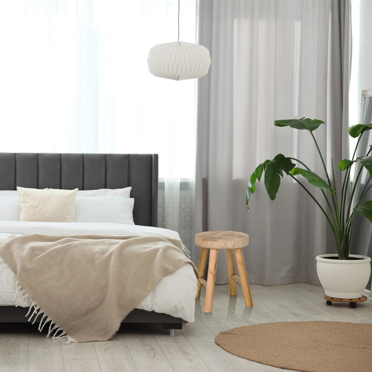Brauner Sitzhocker RUSTIKO W aus Holz mit drei Beinen neben einem Bett von hjh LIVING