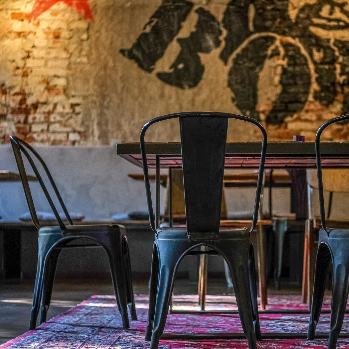 Rückansicht eines schwarzen Bistrostuhls VANTAGGIO BRUSH aus Metall an einem Tisch von hjh OFFICE