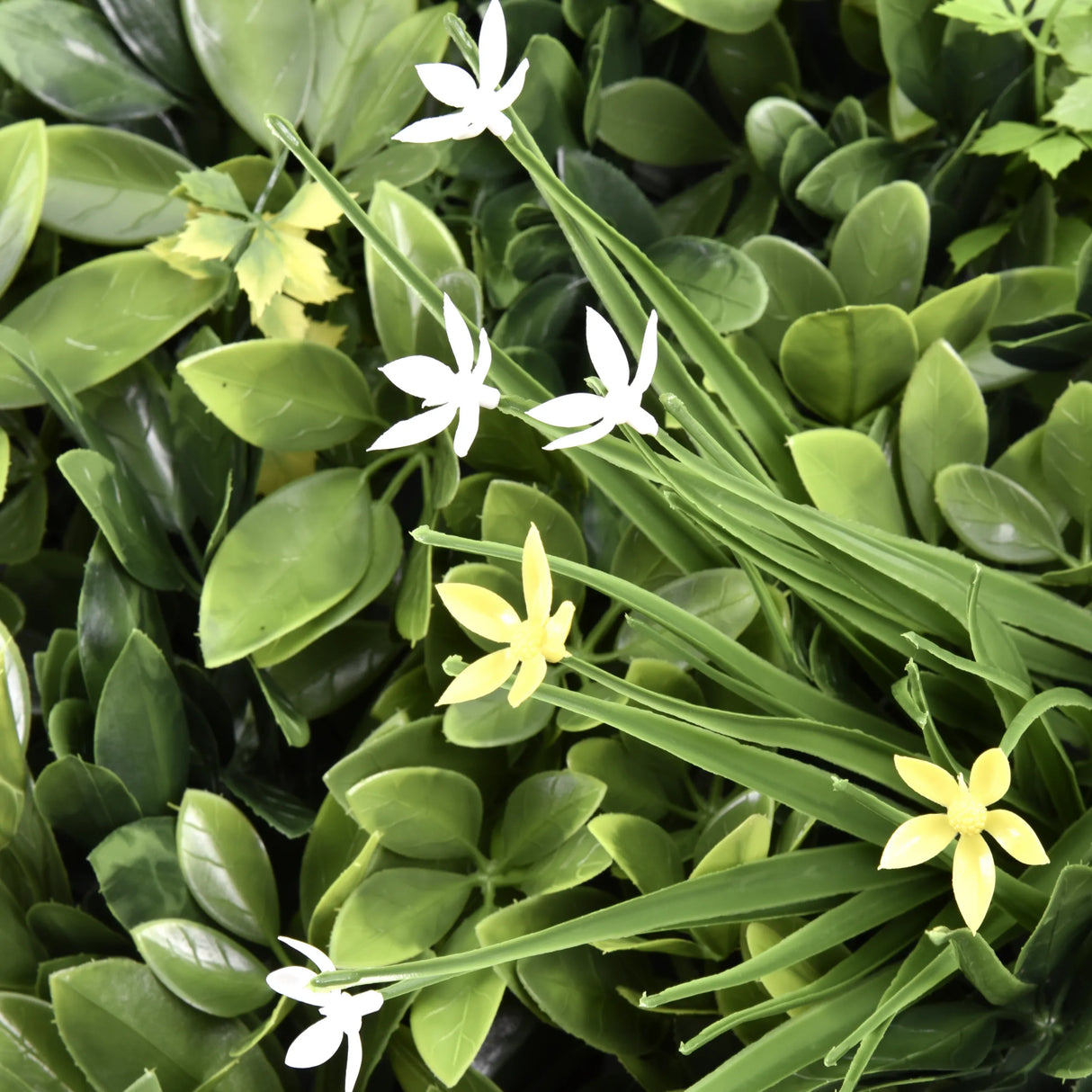 Grüne Blätter mit kleinen weißen und gelben Blüten der Pflanzenmatte LEAFLUXE WALL 2 von hjh LIVING