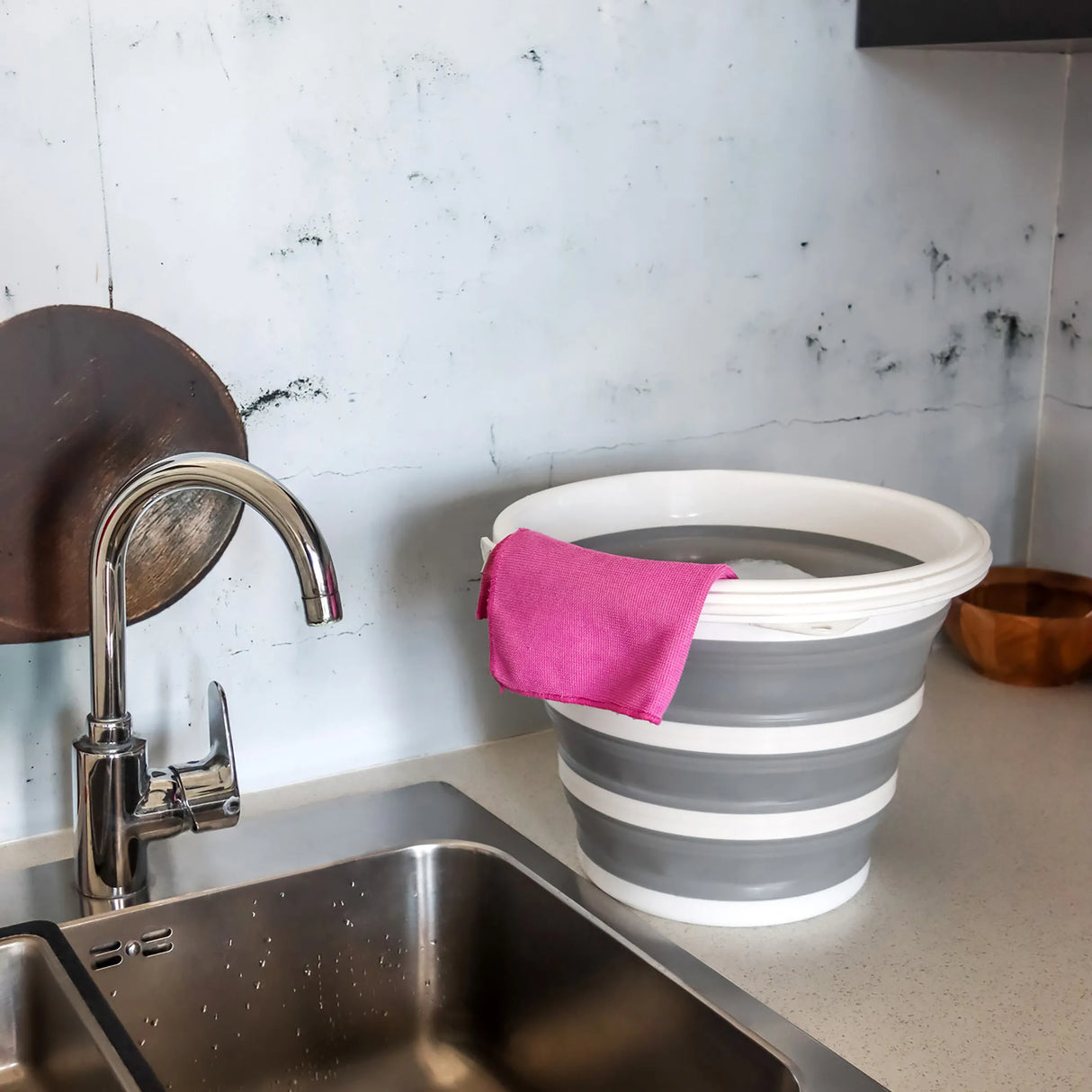 Grau-weißer Faltbehälter CLEAN SILR mit einem rosa Tuch auf einer Arbeitsfläche neben einem Waschbecken von hjh OFFICE