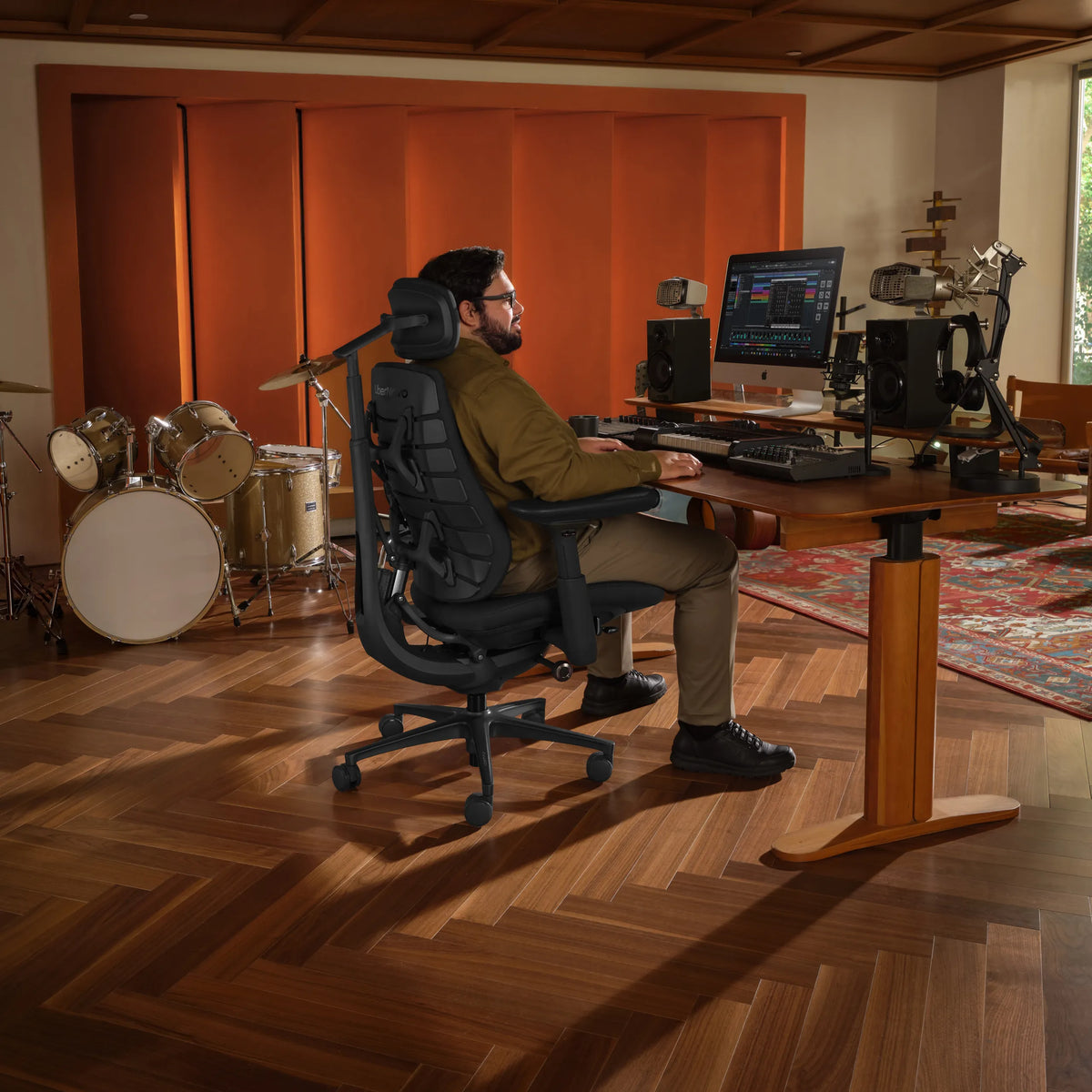 Bürostuhl LiberNovo Maxis Elektric in Graphit in einem Musikstudio mit Schreibtisch und Schlagzeug von Libernovo