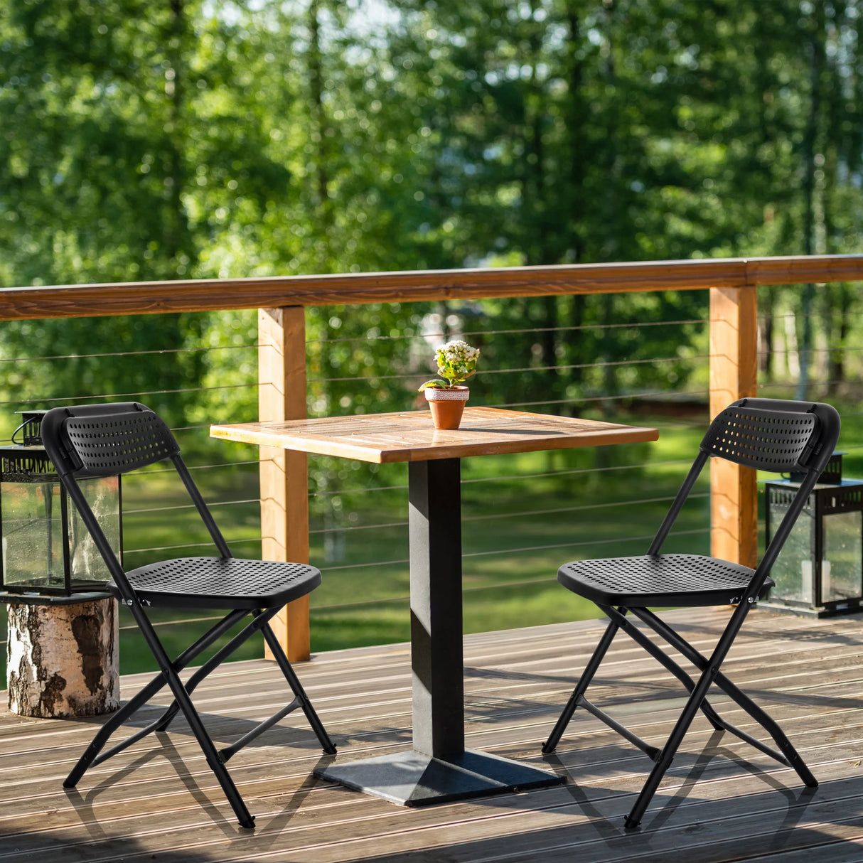Zwei schwarze Outdoor-Stühle TUDELA XXL PRO mit perforierter Sitzfläche an einem Holztisch von hjh OFFICE