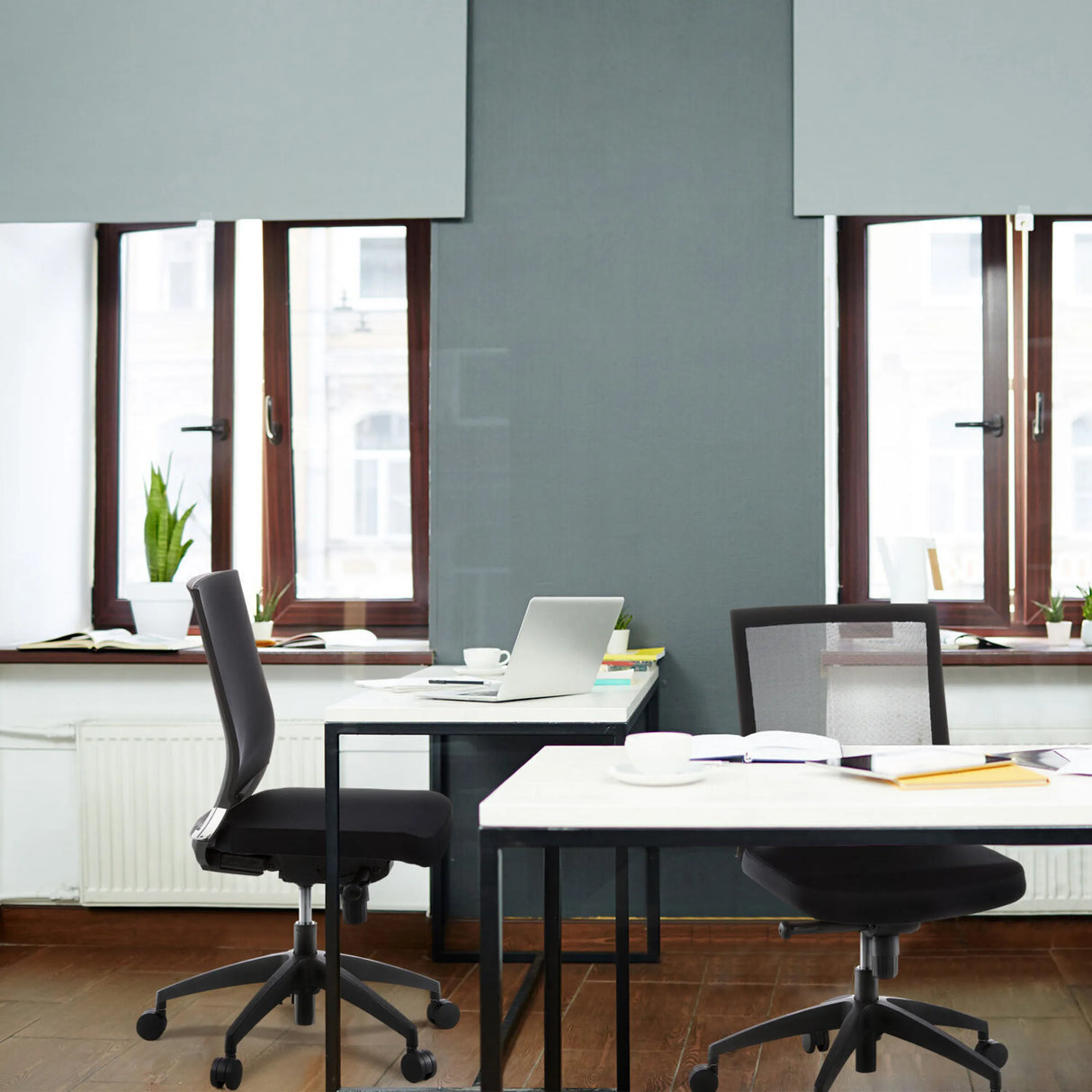 Zwei schwarze Profi-Bürostühle PORTO ECO an weißen Schreibtischen in einem Büro von hjh OFFICE