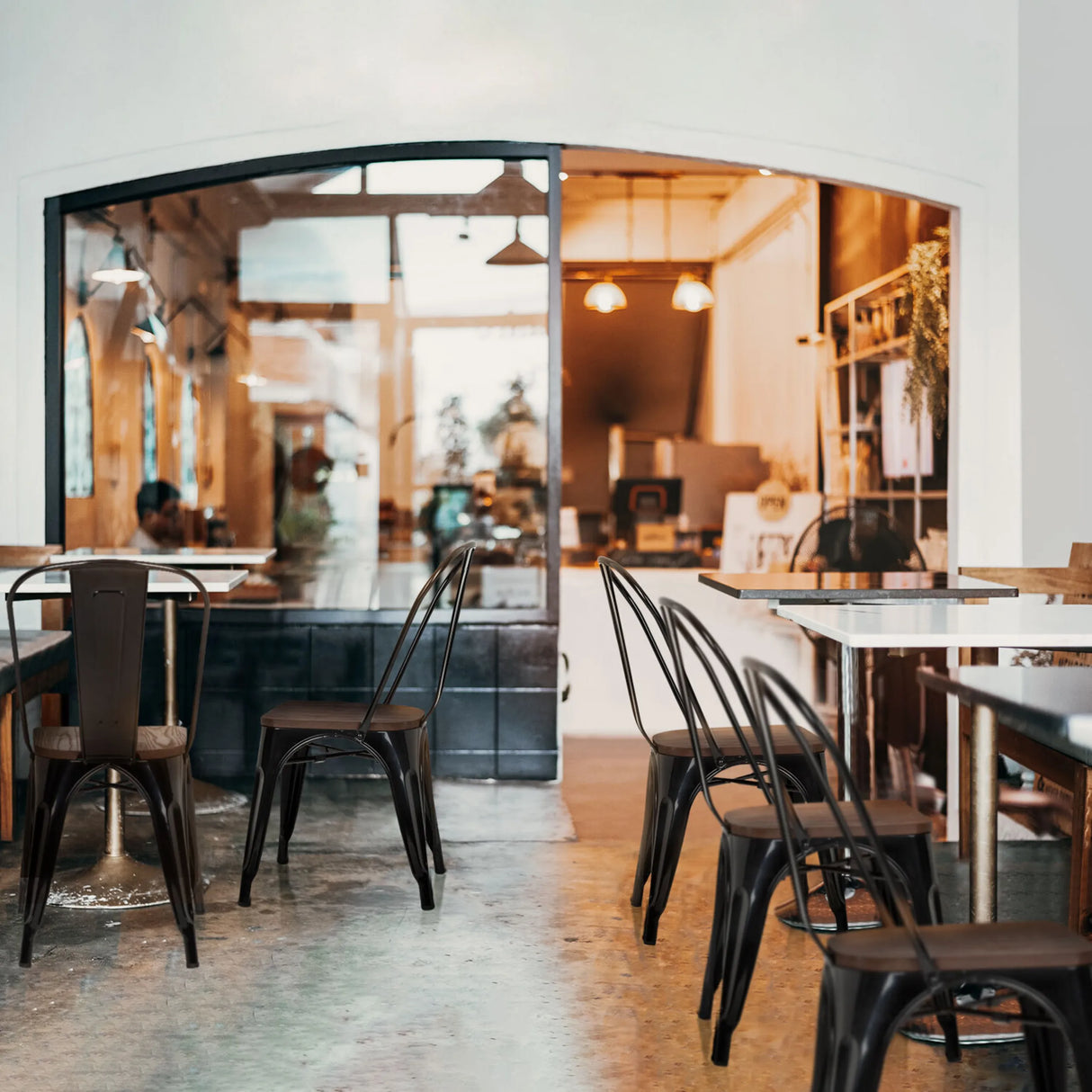 Schwarze Bistrostühle VANTAGGIO COMFORT W mit Metallrahmen an Tischen in einem Café von hjh OFFICE