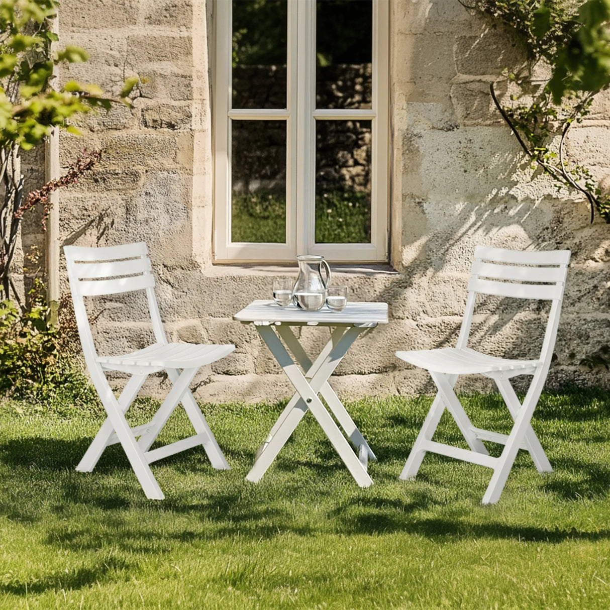 Zwei weiße Outdoor Stühle TRAVANO mit passendem Klapptisch auf einer Rasenfläche von hjh LIVING