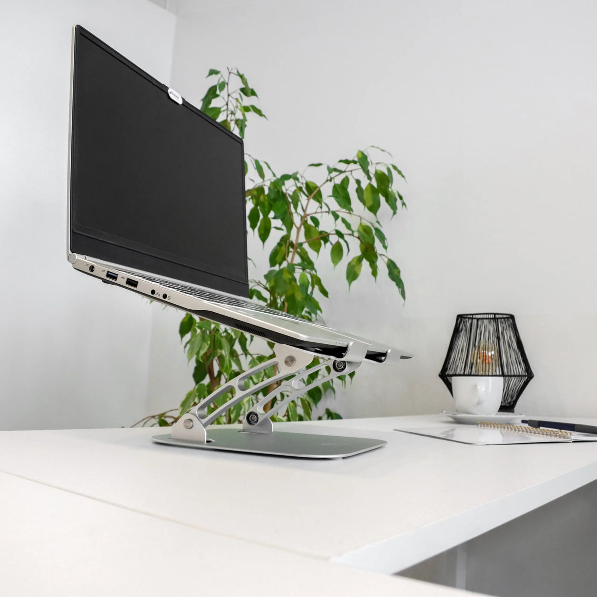 Silberne Laptopunterlage LAPTOP STAND mit höhenverstellbarem Gestell und Laptop auf weißem Schreibtisch von hjh OFFICE
