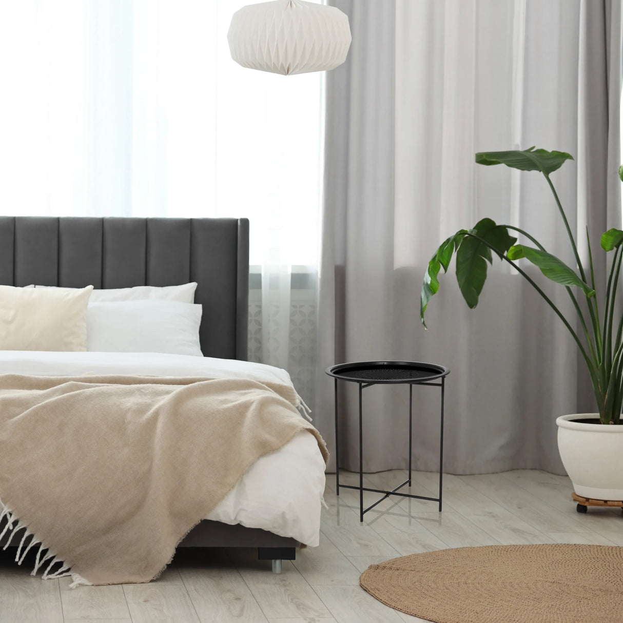 Schwarzer Beistelltisch ALLRUND aus Metall mit einer Platte mit Lochmuster neben einem Bett von hjh LIVING