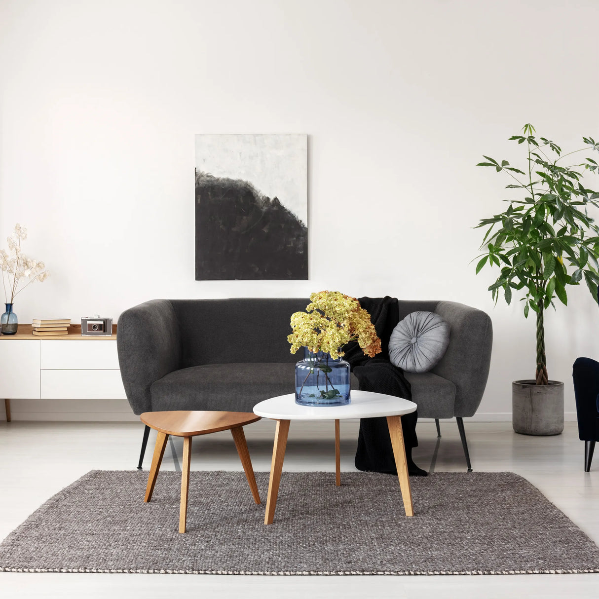 Graues Loungesofa HAYRIVER mit zwei Beistelltischen und einem Teppich in einem hellen Raum von hjh LIVING