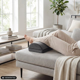Schwarze Fußablage Podi Velvet 1 unter den Beinen einer Person auf einem Sofa von hjh OFFICE (KI-generiertes Bild)