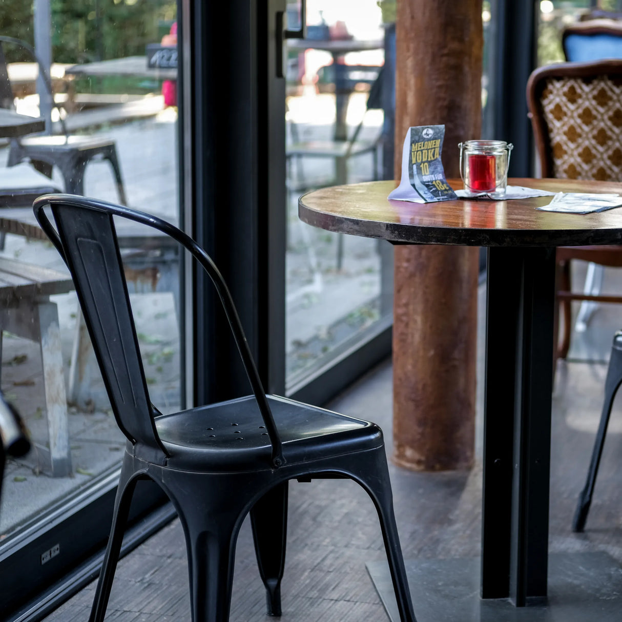 Schwarzer Bistrostuhl VANTAGGIO BRUSH mit geschwungener Rückenlehne an einem runden Tisch von hjh OFFICE