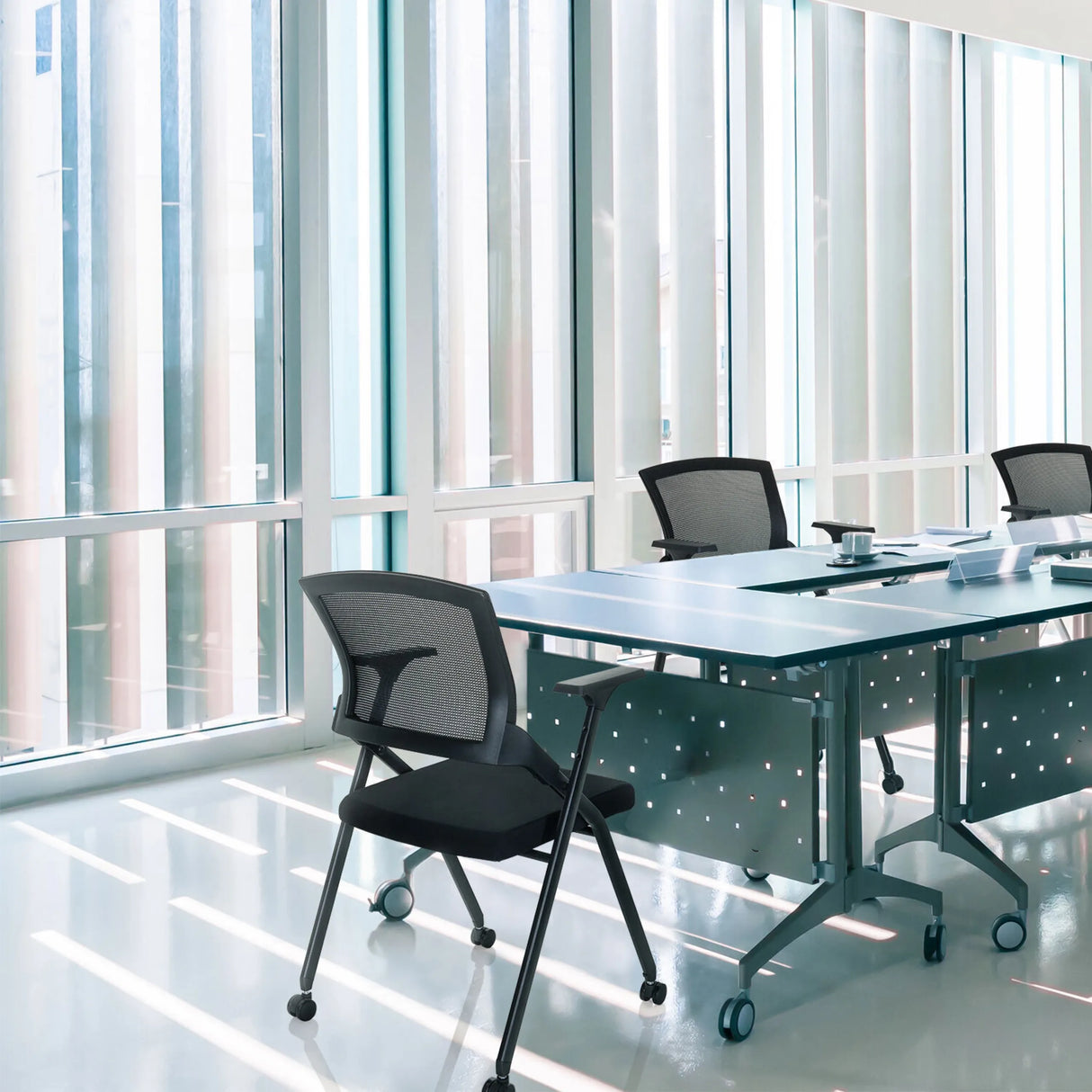 Klappstuhl PRIORITY II in Schwarz mit Netzrückenlehne an einem Konferenztisch von hjh OFFICE