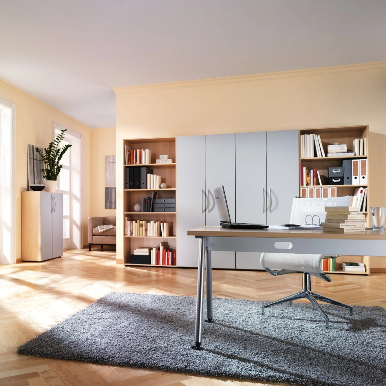 Höhenverstellbarer Schreibtisch ATOS 18 S in Asteiche mit Laptop und Bürostuhl in einem hellen Raum von hjh OFFICE PRO