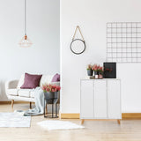 Weiße Kommode ESTHA mit zwei Türen und hellen Holzfüßen in einem hellen Wohnraum von hjh LIVING