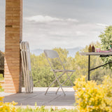Weißer Outdoor-Stuhl TUDELA XXL W in einer Außenansicht neben einem Klapptisch von hjh OFFICE