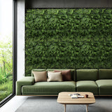 Grüne Pflanzenmatte LEAFLUXE 2 als vertikale Begrünung an einer Wand hinter einem Sofa von hjh LIVING