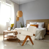 Weißer Loungesessel POOLY mit Holzbeinen in einem hellen Schlafzimmer von hjh LIVING