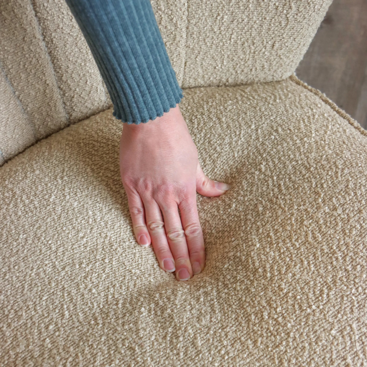 Beiger Strukturstoff des Loungesessels MANISO mit einer auf der Sitzfläche liegenden Hand von hjh LIVING