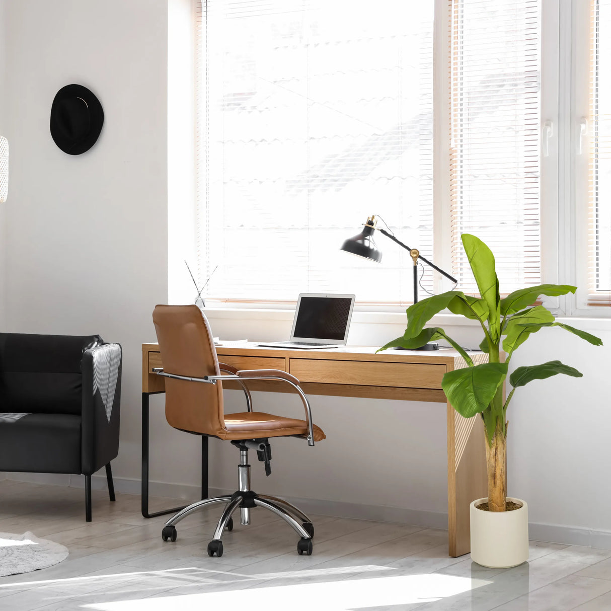 Grüne Kunstpflanze BANANE I in einem hellen Topf neben einem Schreibtisch von hjh OFFICE