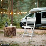 Weißer Outdoor-Stuhl TRAVANO in einer Waldumgebung neben einem Camper von hjh LIVING (KI-generiertes Bild)