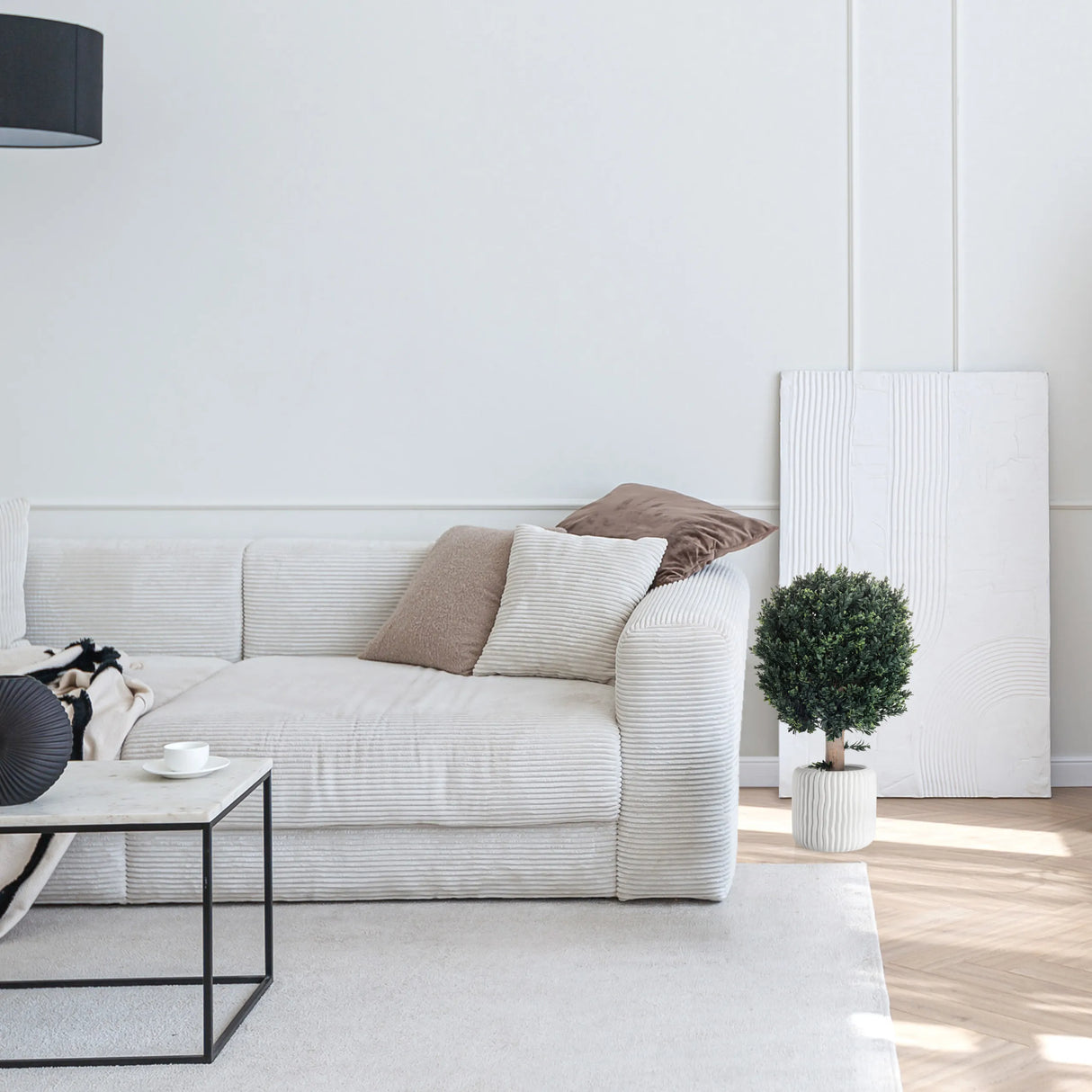 Grüne Kunstpflanze BUXUS in einem weißen Übertopf neben einem Sofa von hjh OFFICE