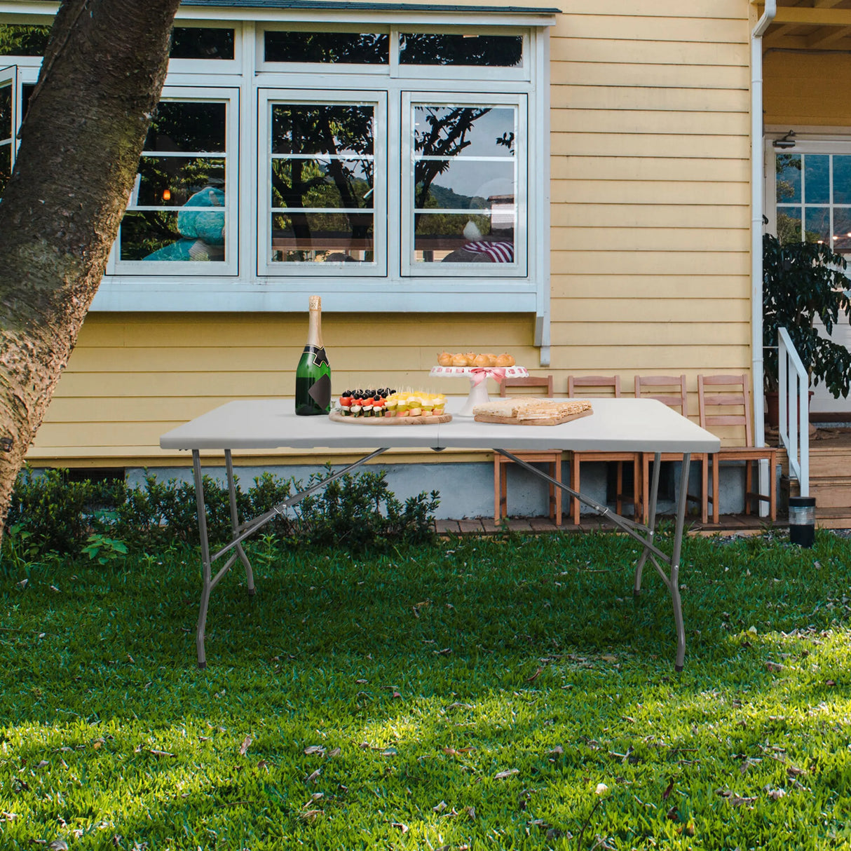 Weißer Klapptisch EASY UP MULTI II in den Maßen 152 x 70 cm auf einer Wiese vor einem Haus von hjh OFFICE